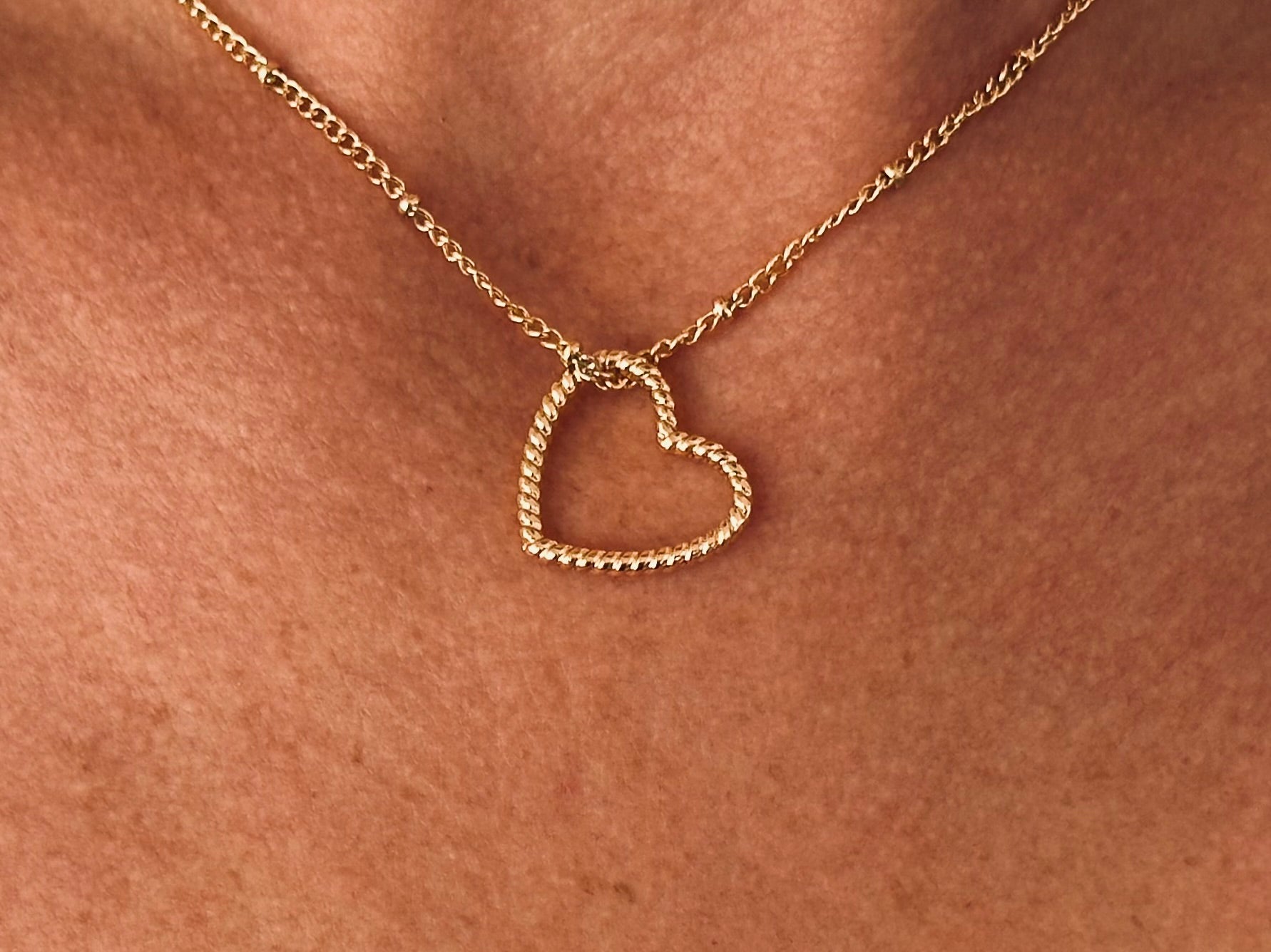 Gold-colored metal necklace with a twisted heart