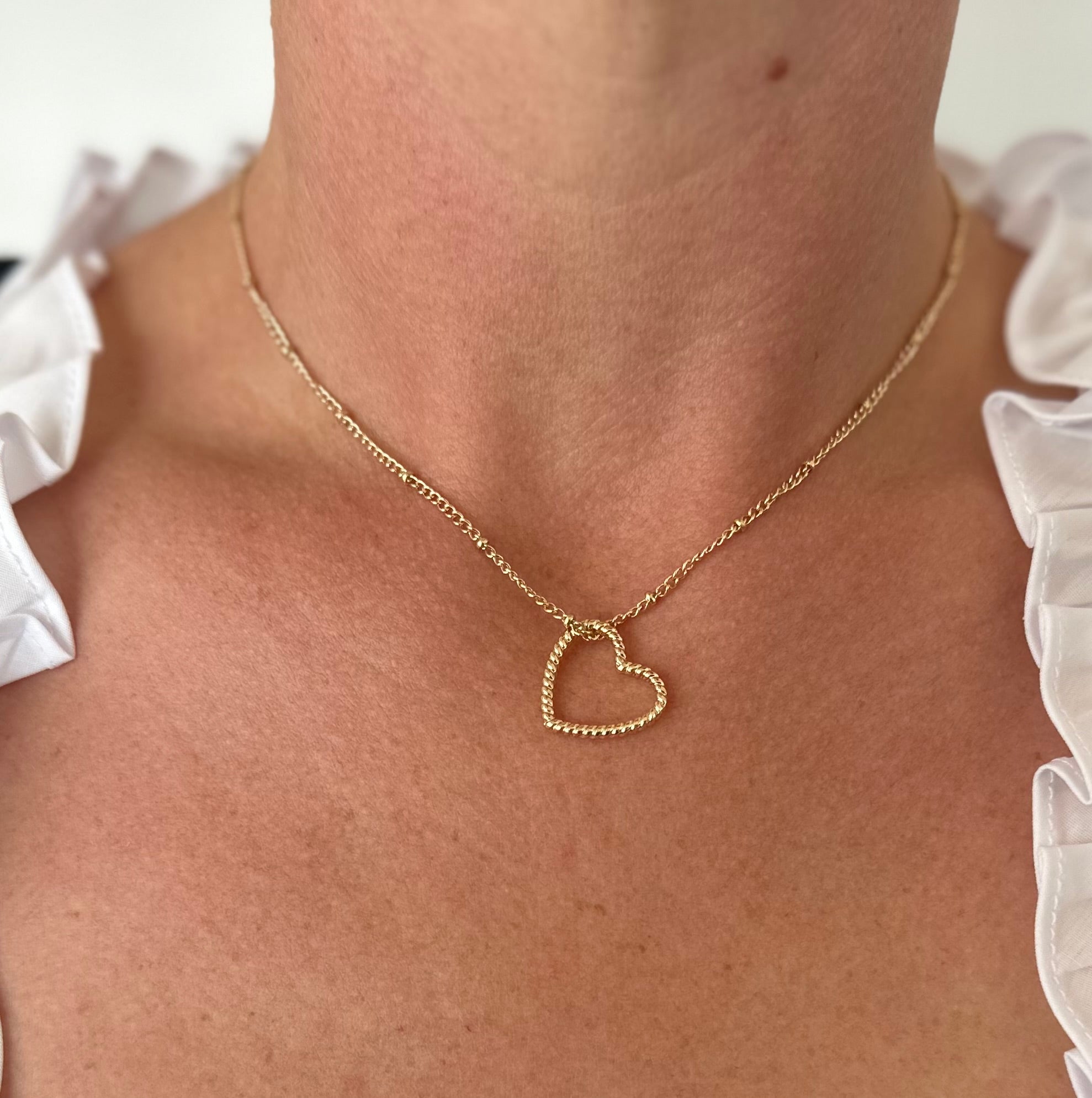 Gold-colored metal necklace with a twisted heart