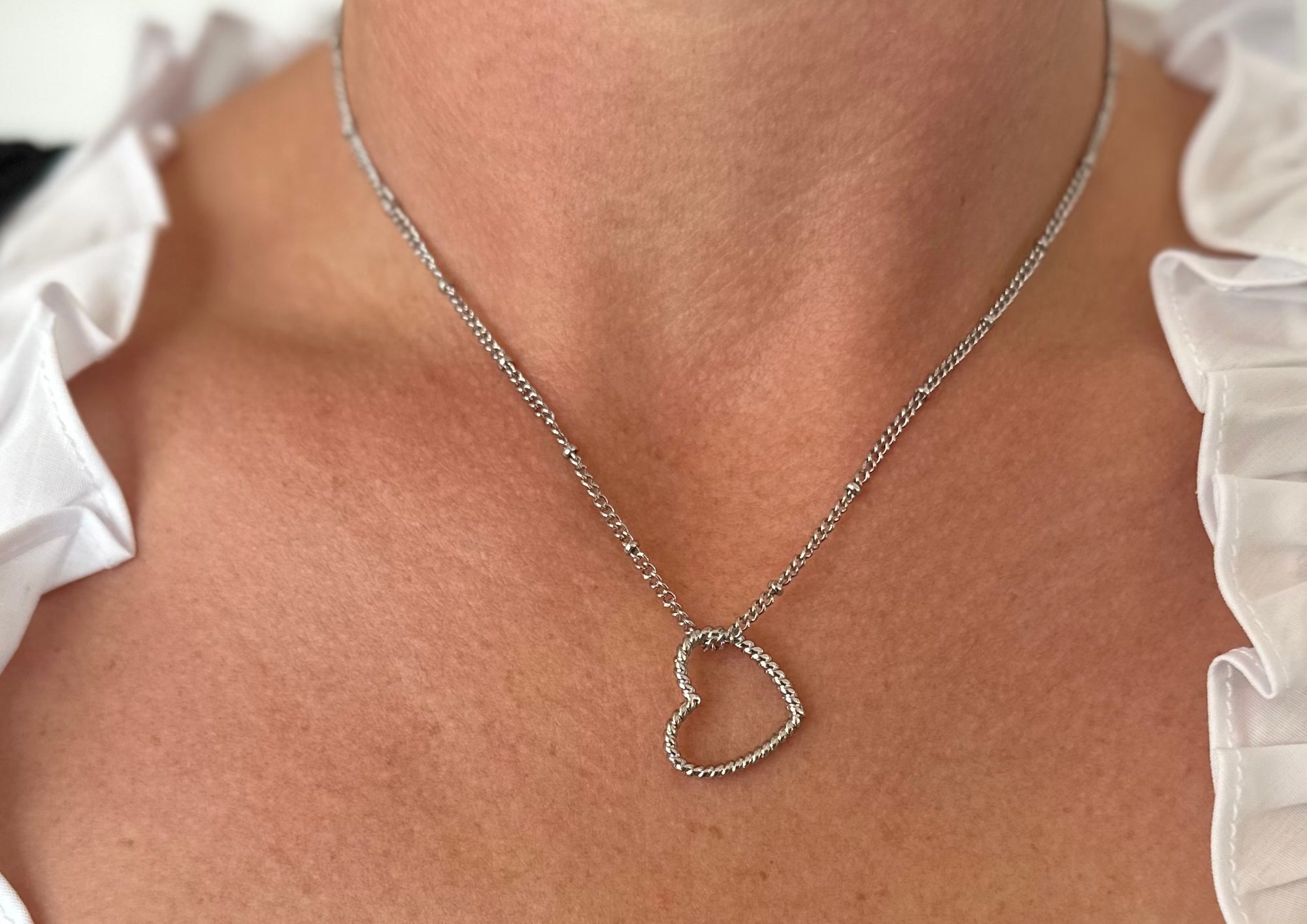 Silver-colored metal necklace with a twisted heart